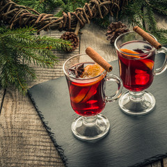 Christmas mulled wine with cinnamon and orange on wooden rustic board. Traditional hot drink at Christmastime.