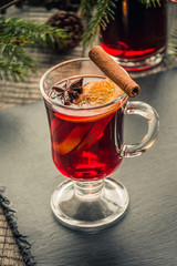 Christmas mulled wine with cinnamon and orange on wooden rustic board. Traditional hot drink at Christmastime.