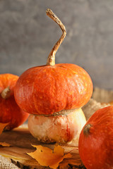 Whole fresh pumpkins with autumn leaves on wooden stump