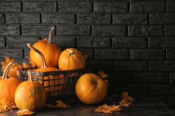 Basket with fresh pumpkins and autumn leaves on wooden table