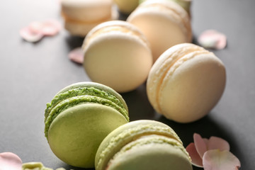 Fresh tasty macaroons with rose petals on grey table