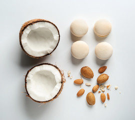 Fototapeta na wymiar Fresh tasty macaroons with cut coconut and almonds on white background