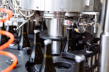Glass bottles on the automatic conveyor line at the champagne or wine factory. Plant for bottling alcoholic beverages.