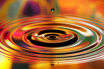 Water drops splash. Red and yellow ripples, reflections on surface