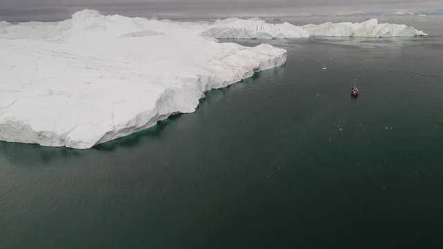 4k 60fps Greenland Aerial view of huge iceberg of Sermeq Kujalleq glacier Ilulissat disko bay with whale watching boat 
