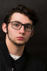 Serious young man wears glasses on black background. Businessman concept.