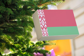 Belarusian flag printed on a Christmas gift box. Printed present box decorations on a Xmas tree branch. Christmas shopping in Belarus, sale and deals concept.