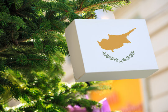 Cypriot flag printed on a Christmas gift box. Printed present box decorations on a Xmas tree branch. Christmas shopping on Cyprus , sale and deals concept.