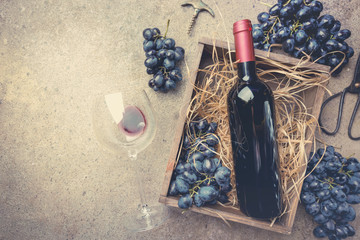 A bottle of red wine with grapes
