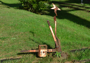 The device of switch translations of a rail, the mechanism with a manual control stands on the street under a bright hot sun, near railway tracks.