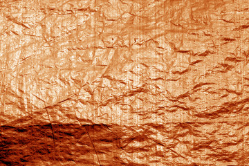 Crumpled transparent plastic  surface in orange color.