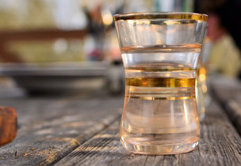 Golden glass cup for alcohol, vodka close-up with blurred background. Bar and kitchen utensils