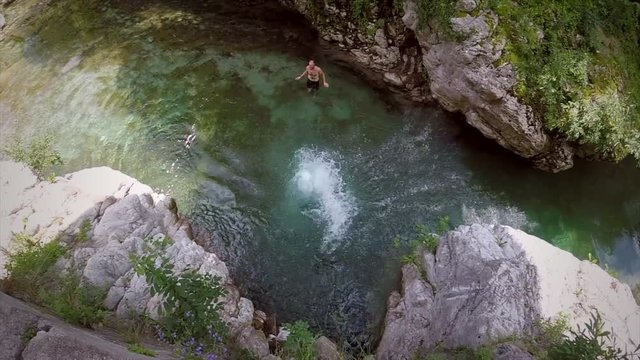 Slow motion of young man jumping from rock into river in Soca valley, Slovenia.
