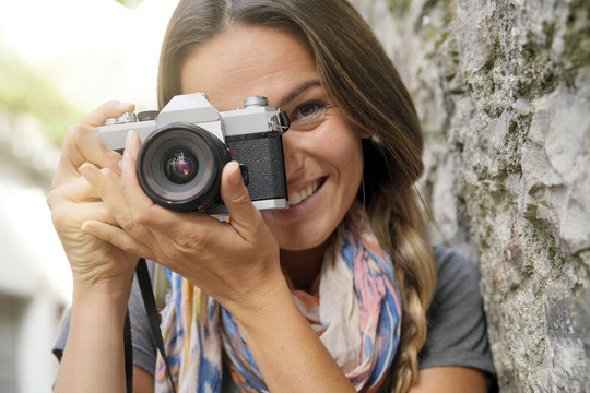 Close up of young woman taking a photo with a vintage camera