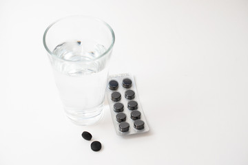 Glas Wasser und Kohletabletten gegen Durchfall