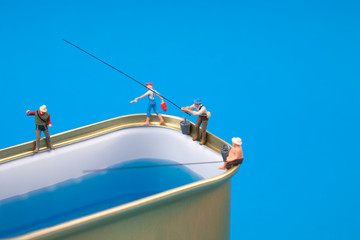 Miniature people fishing on cans
