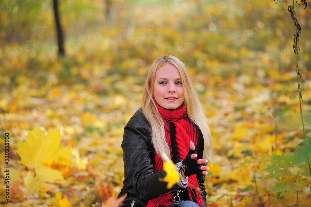 Wall mural blonde in a red scarf and falling leaves