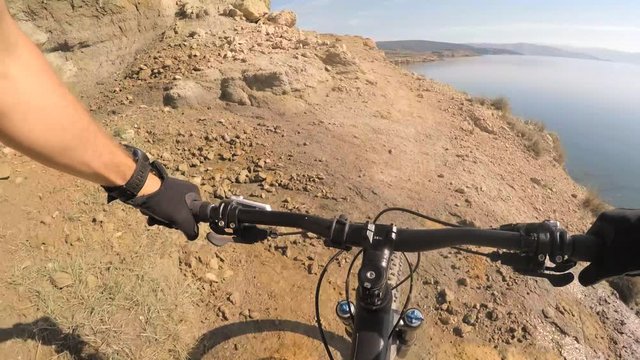 Man riding enduro mountain bike on rocky trail at the seaside in Croatia. View from first person perspective POV. Gimbal stabilized video. Shot with GOPRO HERO4 2.7K.
