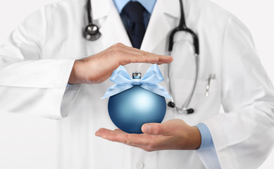 Merry Christmas from doctor,, best wishes concept, hands with xmas blue ball, gift card banner web template with copy space