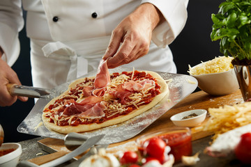 Chef making a prosciutto ham Italian pizza