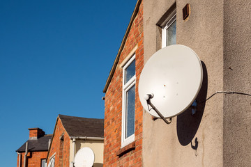 domestic satellite dish on traditional british house wall
