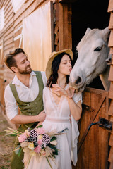 newlyweds dressed boho style standing near horse