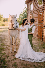 newlyweds dressed boho style standing near horse