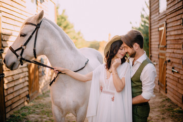 newlyweds dressed boho style standing near horse