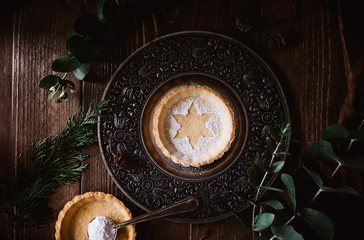 Weihnachtliches Tart mit Puderzucker und Eukalyptus dekoriert auf rustikalem Holz - Weihnachtskarte