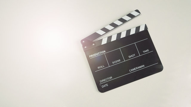Black Clapperboard or clap board or movie slate use in video production , movie, cinema industry on white background with flare light.