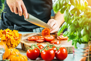 
Chef slicing fresh ripe tomatoes on a board