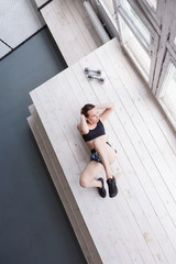 Sporty serious woman doing exercise in gym on floor top view