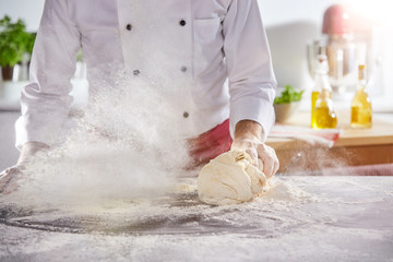 Cloud of flour kicked up by man rolling dough