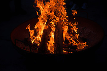 Feuerpfanne mit brennenden Holzscheiten in der Nacht