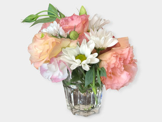 A bouquet of flowers in a glass cup on white.