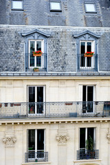 Old parisian house facade with french balconies, geraniums in flowerpots