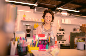 My workplace. Positive delighted young woman keeping smile on her face while meeting guests