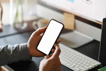Businessman using mobile phone on desk, Smart phone showing blank screen for montage.