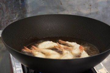 Cooking fried prawn with tempura flour in a hot black pan