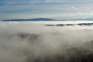 A beautiful view of the hills in Tuscany submerged by a morning mist that gives a magical touch to the scene from the top of one of the towers of San Gimignano