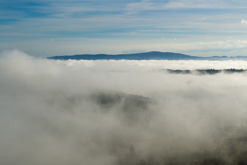 A beautiful view of the hills in Tuscany submerged by a morning mist that gives a magical touch to the scene from the top of one of the towers of San Gimignano
