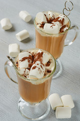 Traditional hot winter drink or healthy Christmas cocktail - spicy latte or cocoa with chocolate powder and marshmallows in the glasses on the gray concrete background. Side view