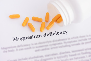 Magnesium deficiency diagnosis on paper with pills spilling out of a bottle