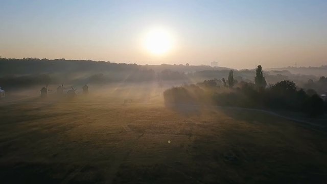 Nature foggy landscape scene. Beautiful rural panorama. dawn and fog. Mill and church in the field. Morning in the Ukrainian village countryside. Video aeriel drone footage. Amazing sinrise