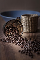 Coffee grains are scattered on a wooden table in the morning light in a rustic style.