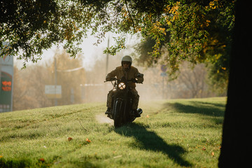 young man on a motorcycle rides through green grass