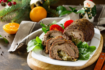 Stuffed Beef Roll with Pear and Cheese on a festive Christmas table. Copy space.