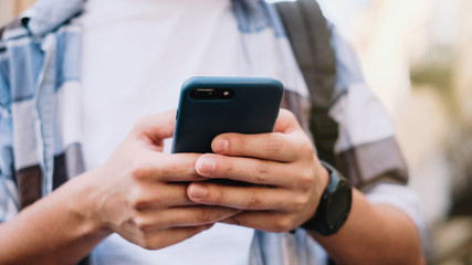young man using his mobile phone in city. Close up of a man usin