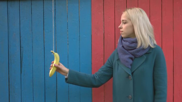 Girl with a banana phone.
Girl stands and looks into the camera, then a banana phone comes down from above on a string and girl answers the call and smiles. Surrealism.