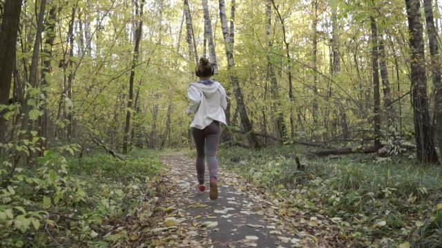 The girl runs slowly along the forest path.

